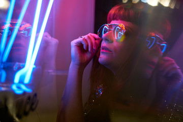 girl with sunglasses and fringe looking at neon lights