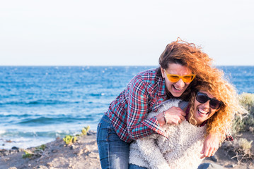 Couple of adult nice caucasian women play together carrying eachother with lot of fun and laughs -...