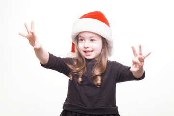 Obraz na płótnie Canvas Happy girl in santa hat on white background. Funny young child waiting for christmas, new year and presents. holiday, sale concept with place for text