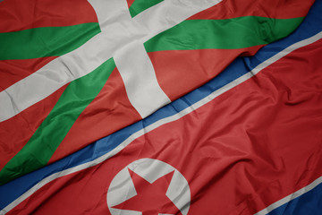 waving colorful flag of north korea and national flag of basque country.