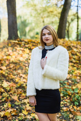 Fashion dresses woman in fur coat and dress posing in autumn park