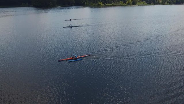 Canoeing competition-rowing boating sport. Athletes girls rowers on outrigger canoe boats with stabilizer in the river water area. Aerial survey 