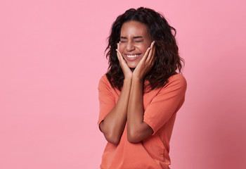 Excited beautiful african woman happiness wearing casual orange t-shirt isolated on pink background.