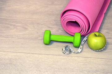 Healthy lifestyle. Dumbbells, Yoga mat, green apple and measuring tape. Sport. Lifestyle.