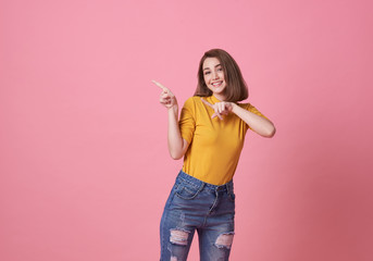 Happy young woman standing with her finger pointing isolated over pink banner background with copy...