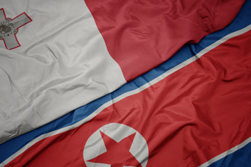 waving colorful flag of north korea and national flag of malta.