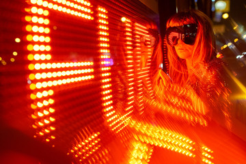 Woman in sparkling dress and reflective snowboard glasses looking at led lights