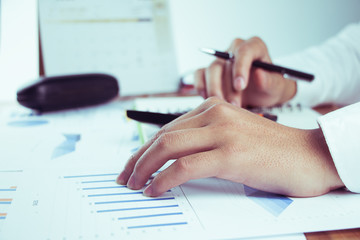 business people who use a calculator with financial concepts, spreadsheet data, business people use their fingers to compute calculations