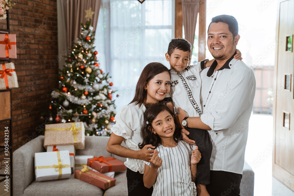 Wall mural asian family with two children in livingroom with christmas tree