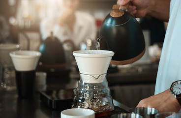 Barista poured hot water from the kettle into the glass jar to make coffee.