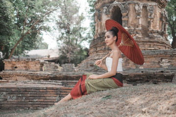 Obraz premium Beautiful Thai women wearing traditional Thai clothes holding ancient red umbrellas in temples Thailand, woman concept