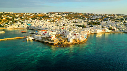 Naklejka na ściany i meble Aerial drone panoramic photo of picturesque old port in main village of Mykonos island at sunset and iconic church of Paraportiani with beautiful colours, Cyclades, Greece