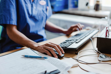 Midsection of nurse using computer at desk in hospital