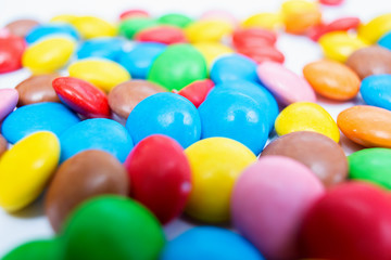 Many multi-colored small round candy pills are scattered on the table close-up