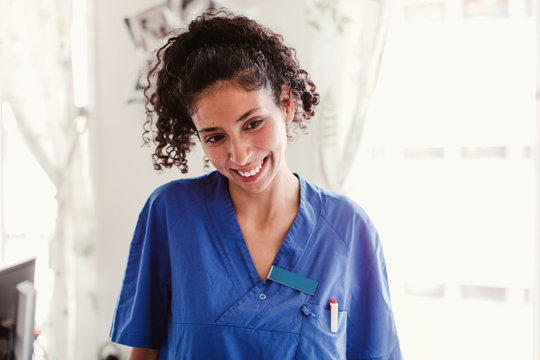 Smiling nurse with curly hair looking away in hospital