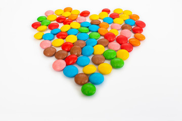 Multicolored round jelly beans collected in the form of a heart on a white background