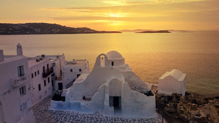 Aerial drone panoramic view of landmark church of Paraportiani overlooking the Aegean sea in main village of Mykonos island at sunset with beautiful colours, Cyclades, Greece
