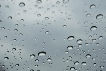 Rain drops on window glasses surface with cloudy background