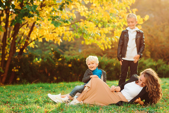 Young loving mother with her two sons spending free time outdoors. Family, autumn fashion and lifestyle