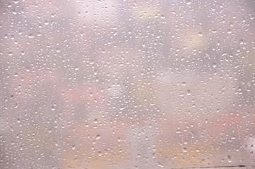Window with rain droplets and grey sky in background