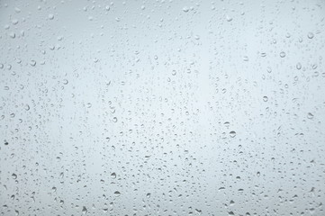 Window with rain droplets and grey sky in background