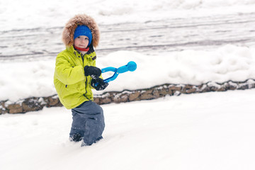 Fototapeta na wymiar Cute child playing with snow in winter park. Snowy cold winter weather. Family winter vacation.