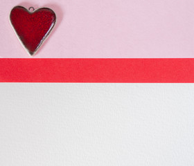 Red ceramic Valentines hearts on a pink and white paper background