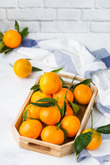 Fresh orange mandarins, tangerines with green leaves on a table
