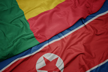 waving colorful flag of north korea and national flag of benin.