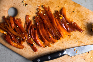 Overhead view of sliced roasted red peppers on cutting board
