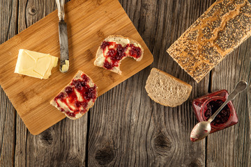 fresh bread with butter and fruit marmelade served on wooden plate, breakfast in rustic style