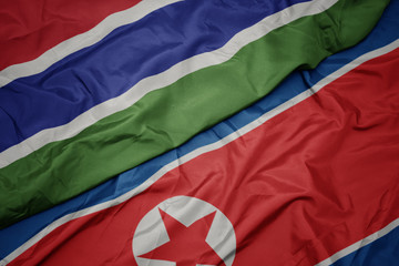 waving colorful flag of north korea and national flag of gambia.