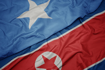 waving colorful flag of north korea and national flag of somalia.