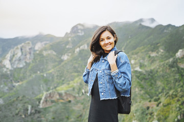 Naklejka na ściany i meble Happy smiling woman with backpack on in the mountains. Travel and lifestyle concept