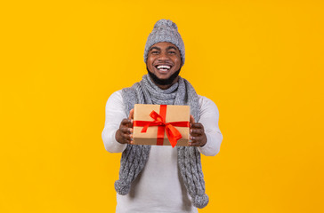 Cheerful young black man giving christmas gift