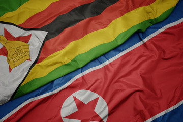 waving colorful flag of north korea and national flag of zimbabwe.