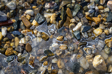 Stones on the shore and the crust of the first ice on the water. First frosts.