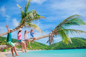 Happy family on the beach on palm tree during summer vacation