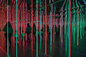 Silhouettes of people among the bright light lines in the mirror maze.