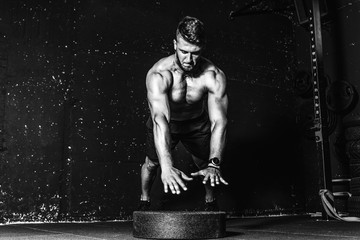 Young fit muscular man with big sweaty muscles doing push ups cross workout training with clap his hand above the barbell weight plate on the gym floor with motion blur black and white