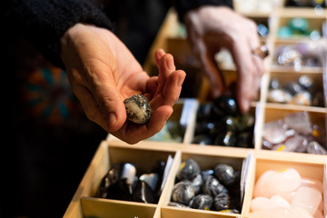 close up of woman hands picking up precious stones at stones trade show display from shelves