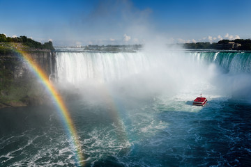US spectators at Tarrapin Point with double rainbow and Hornblower tour boat in most of Horseshoe Falls at Niagara Falls Ontario Canada