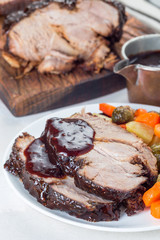 Pork shoulder in honey parmesan and soy souse, prepared in slow cooker or crockpot, served with carrot, potato and brussel cabbage, on  white plate, vertical , closeup