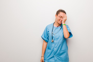 young latin nurse laughing and slapping forehead like saying d‚Äôoh! I forgot or that was a...