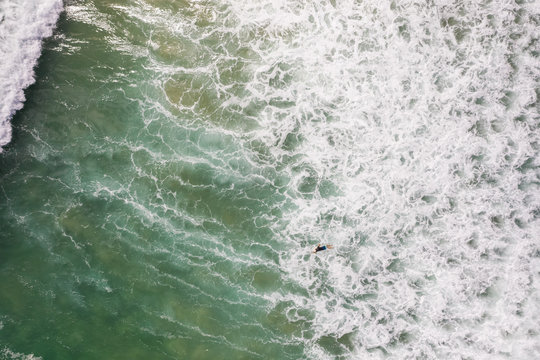 Aerial view of man surfing on the agitated sea at Alexandria Bay, Australia.
