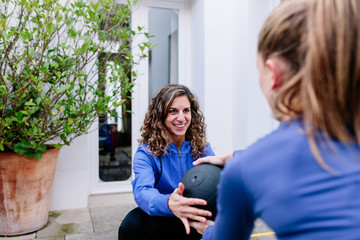 Two young women doing exercise together with medicine ball