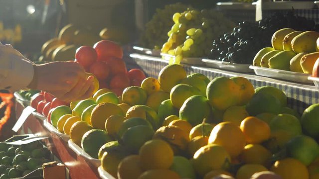 Local farmer's fruit market scene. Woman buying fresh fruits at the local market, beautiful summer sunset view, organic farming concept. Colorful raw fruits, vegetarian concept.