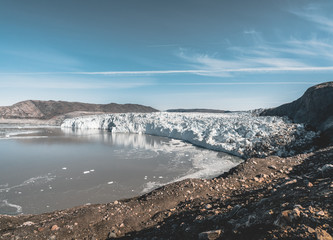 Greenland, Eqip Sermia, Eqi Glacier in Greenland Disko Bay. Boat trip in the morning over the arctic sea,Baffin Bay, calving glacier. Ice breaking of on a blue sky wth clouds.
