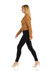 Young Woman In Brown Suede Jacket Is Walking And Looking Away. Side View.