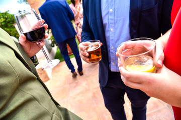 Guests at an event hold glasses with drinks and cold beers while they talk about business and...